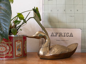 vintage brass duck statue next to house plant and in front of a vintage map of africa