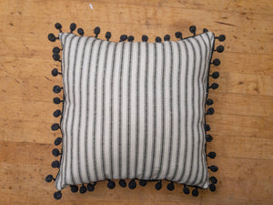 black and white ticking stripe pillow with black pom pom trim