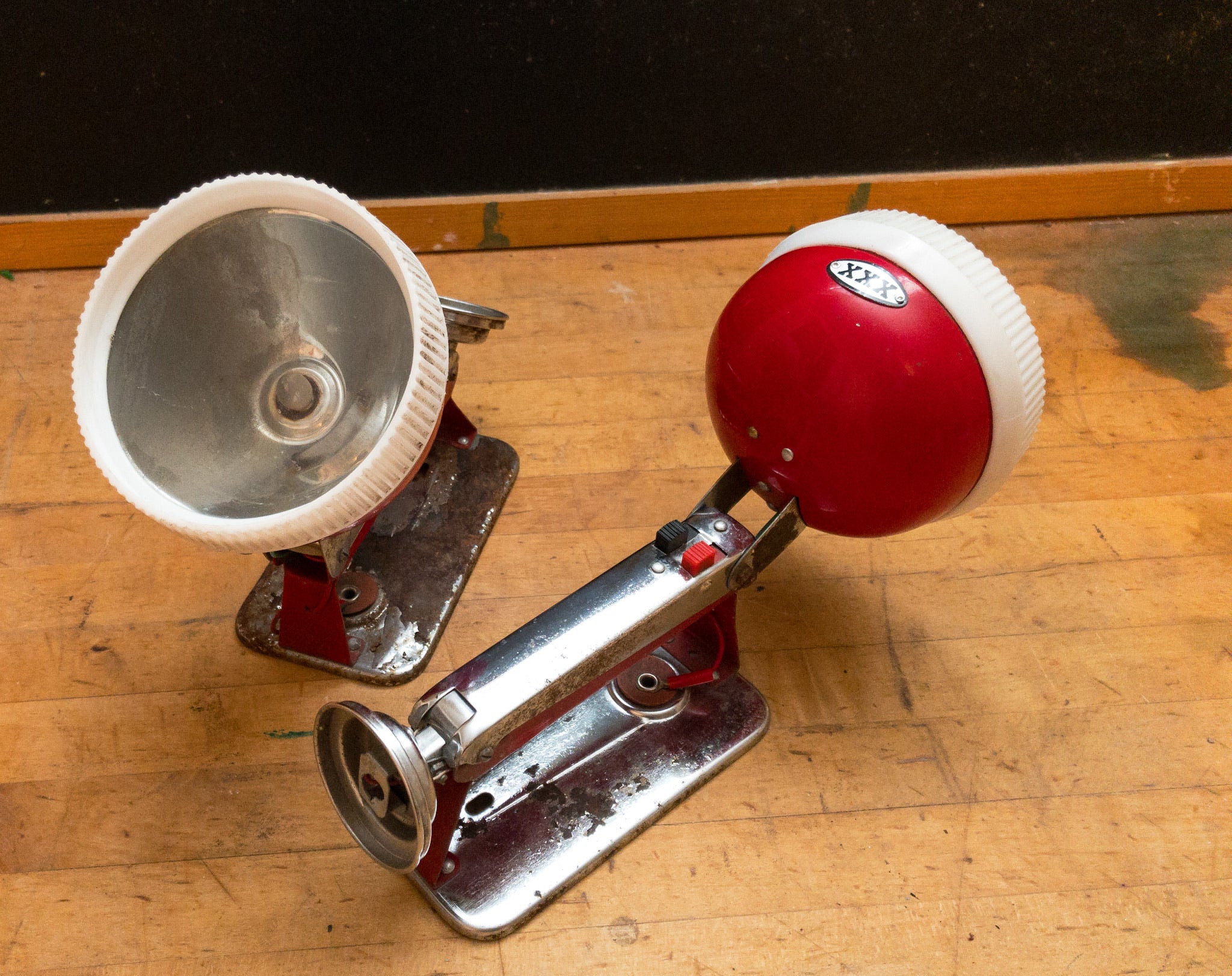 Two vintage red white and silver flashlights sitting on a wood desk