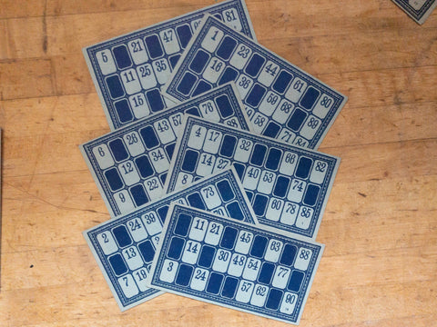 six horizontal blue vintage bingo game cards fanned out on a wood table