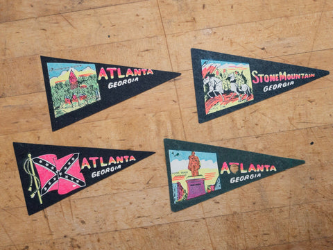 four small black and green felt pennants featuring landmarks and flag from the state of Georgia USA on a wood table