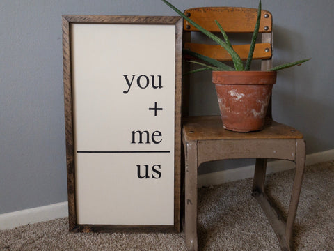 white flash card wood sign with black text and with dark brown frame sitting on the floor next to a vintage school chair and a green aloe plant